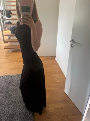Svart långklänning från Wera - Säljer en elegant svart långklänning från Wera. Klänningen har en figurnära passform och är ärmlös med rund halsringning. Perfekt för dig som vill ha en stilren och tidlös look. Jag är 166 cm
