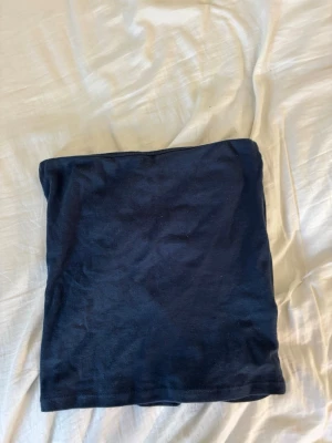 Mörkblå bandeau topp från Subdued - En enkel och stilren mörkblå bandeau topp från Subdued. Toppen är axelbandslös och har en tight passform, perfekt för att matcha med höga jeans eller kjol. Tillverkad i mjuk bomull för en bekväm känsla.