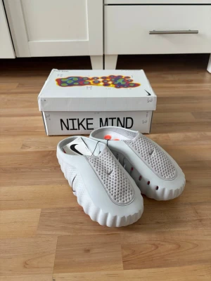 HELT NYA! Nike Mind 001 vita tofflor - Säljer dessa helt nya Nike mind tofflor då tiden att lämna tillbaka dem hade gått ut och jag aldrig hade använt dem. Dem går för nypris runt 2000 - 3000 i Sverige och jag säljer dom för endast 1499 då jag vill bara ha dom sålda.                                          Priset kan diskuteras vid en snabb affär.