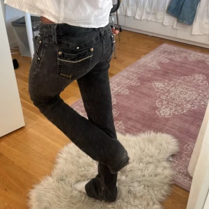 Svarta jeans - Snygga väldigt lågmidjade jeans med gulddetaljer💘 Midja rakt över:36cm  Innerbenslängd: 76cm Obs lite slitningar längst ner men som lätt kan fixas hoss skräddare 