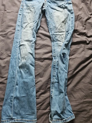 Blå bootcut jeans med slitningar från gina tricot - Ett par klassiska blå bootcut jeans med slitningar och ljusare partier på låren. Jeansen har fem fickor och är tillverkade i denim. Passar perfekt för dig som gillar en avslappnad och trendig stil. Storlek 152