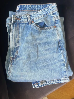 Ljusblå raka jeans från Lindex - Säljer ett par ljusblå raka jeans från Lindex, modell Betty. Klassisk femficksdesign med orangea kontrastsömmar och dragkedjegylf. Perfekta till en avslappnad och trendig look. Tillverkade i slitstark denim.