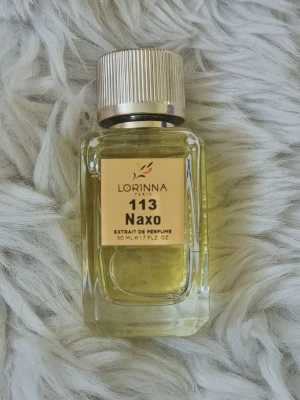 Lorinna 113 Naxo Extrait de Parfum - Lorinna 113 Naxo Extrait de Parfum är en exklusiv parfym i en stilren, genomskinlig glasflaska med guldfärgat lock. Flaskan rymmer 50 ml och har en elegant etikett i guldton. Parfymen levereras i en matchande guldfärgad kartong.