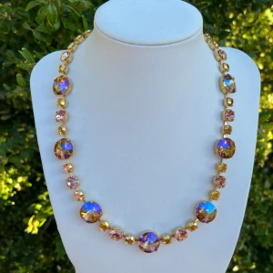 Halsband kristaller  - Halsband med blandade kristaller Aurora, Preciosa, Swarowski. Guldpläterad mässing. Färg, Light Smoked Topaz Shimmer, Rose Peach och Crystal Sunrise. SS39 8mm, ss29 6mm och Rivoli 14 mm stora kristaller. Längd 51cm inkl lås och förlängningskedja. Sista bilderna visar andra halsband som finns i lager som jag gjort. Jag skickar endast spårbart, samfraktar. Fast pris. Besök gärna mina övriga annonser.  Till mina smycken använder jag kristaller från Preciosa, Aurora och Swarowski.
