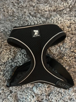Svart sele från Feel Active - Säljer en svart sele från Feel Active med reflexdetaljer och justerbara band. Selen är tillverkad i ett ventilerande meshmaterial och har ett spänne för enkel på- och avtagning. Perfekt för promenader med hund eller katt.