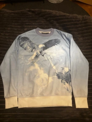Trapstar sweatshirt  - Unik ljusblå sweatshirt från TRAPSTAR med stort tryck av två örnar på framsidan. Tröjan har vita muddar vid ärmslut och nederkant samt rund halsringning. Använd cirka 1 månad. Passar xs/s. Hör av dig vid funderingar🙌🙏