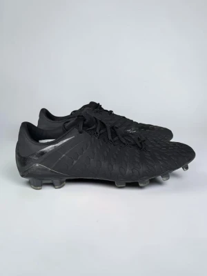 Nike Hypervenom Phantom “Blackout” – helt nya, aldrig använda! - Storlek: 44  Säljer dessa i det stilrena helsvarta utförandet – ett tidlöst “blackout”-tema utan störande detaljer, snyggt och diskret på plan. Dynamic Fit-kragen ger en sockliknande passform runt ankeln för extra stöd och känsla i varje touch.  ✅ Helt nya, sprillans oanvända – inga spår av slitage ✅ Storlek 44 ✅ Äkta vara, köpta direkt från auktoriserad återförsäljare  Perfekta för dig som gillar ett minimalistiskt och elegant utseende utan att kompromissa på prestanda. Passar gräs (FG-dubbar).