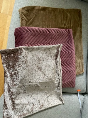3 kuddfodral i sammet, olika färger - Tre kuddfodral i mjuk sammet, en i beige, en i brun och en i dammrosa med fiskbensmönster. Perfekta för att ge soffan eller sängen en mysig och trendig känsla. Storlek: se bilder