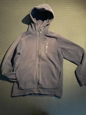 Mörkblå sail racing - Snygg mörkblå hoodie med dragkedja och huva. Utsidan är slät medan insidan är mjukt fleecefodrad för extra komfort. Långa ärmar med muddar och praktiska fickor på sidorna. Perfekt för chill dagar eller när du vill ha något bekvämt.