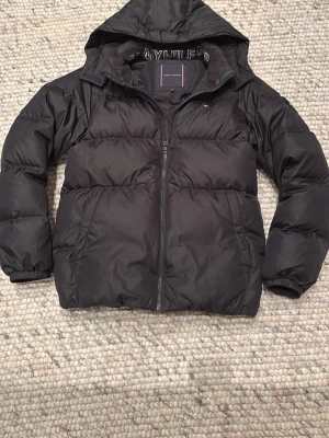 Svart puffer jacka från Tommy Hilfiger - Svart vinterjacka från Tommy Hilfiger med luva. Nypris cirka 2250kr 