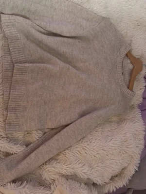 Beige stickad tröja med rund hals - Mysig beige stickad tröja med rund hals och långa ärmar. Tröjan har ribbstickade muddar vid ärmslut och nederkant, vilket ger en klassisk och enkel look. Perfekt för lager på lager under kyliga dagar.