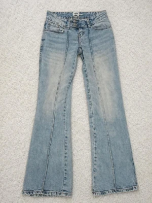 Ljusblå bootcut jeans med pressveck - Säljer ett par ljusblå bootcut jeans med markerade pressveck framtill. Jeansen har klassisk femficksmodell, låg midja. Materialet är denim i bomull och passformen är rak med utsvängda ben. Perfekta för en avslappnad och trendig look. Flare jeans.