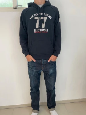 Mörkblå Helly Hansen hoodie - Mörkblå hoodie från Helly Hansen med ett fett tryck på bröstet och HH-logga på ärmen. Skön avslappnad passform perfekt till hösten. Storlekslappen är borttagen men skulle säga storlek M. Hör av dig vid frågor!🙌