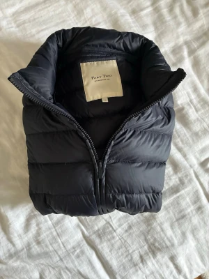 Marinblå dunjacka från Part Two - Snygg marinblå dunjacka från Part Two med quiltad design och hög krage. Jackan har dragkedja framtill och är lätt vadderad för extra värme. Perfekt för höstiga dagar och enkel att matcha till olika outfits.