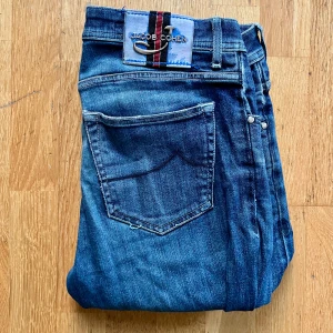 Jacob Cohen blå jeans Style 622 - Snygga blå jeans från Jacob Cohen, modell Style 622 Special Edition. Jeansen har klassisk femficksdesign, slitningar och hål på vänster knä vilket är design av Jacob Cohen. Tillverkade i mjukt denim med detaljerade sömmar och exklusiv patch bak i midjan. Storleken är 34, vilket är som W31 L34 i vanlig jeans storlek. Pris kan diskuteras vid snabb affär. Hör av dig om du undrar något!