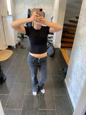 Svart croppad t-shirt - En enkel och stilren svart croppad t-shirt med rund hals och korta ärmar. Perfekt till jeans eller kjol för en avslappnad look. Tillverkad i mjukt bomullsmaterial som känns skönt mot huden.