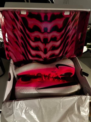 Nike fotbollsskor rosa och vita - Säljer ett par grymma fotbollsskor från Nike i en snygg rosa och vit färgkombination med svart swoosh. Skorna har en låg profil, snörning och genomskinlig sula med dobbar för bra grepp på planen. Perfekta för dig som vill sticka ut på matchen!