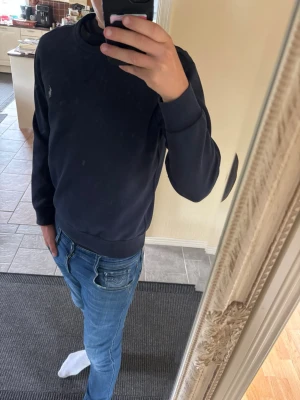 Mörkblå sweatshirt Ralph Lauren - Säljer en stilren mörkblå sweatshirt med rund hals och ribbade muddar. Tröjan har en liten broderad logga på bröstet och är tillverkad i mjukt bomullsmaterial. Perfekt för en avslappnad och snygg look.