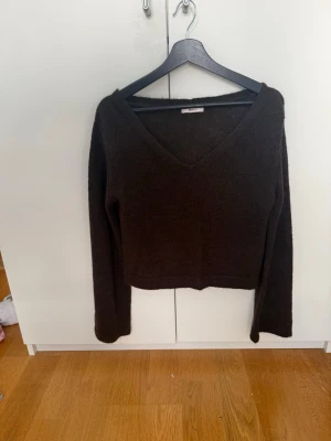Mörkbrun stickad V-ringad tröja - Mysig mörkbrun stickad tröja med V-ringning och långa lite vidare ärmar. Tröjan är tillverkad i ett mjukt material som känns skönt mot huden. Perfekt att styla till olika outfits.