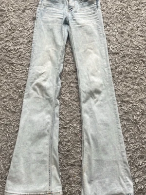 Cheap Monday jeans  - Säljer ett par ljusblåa bootcut jeans från Cheapmonday med coolt tryck på bakfickan. Jeansen har klassisk femficksdesign, låg midja och utsvängda ben. EUR 24/32 