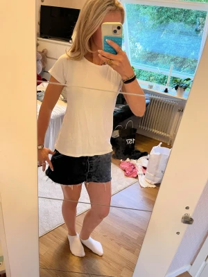 Vit basic t-shirt i bomull - En enkel och stilren vit t-shirt i mjuk bomull. T-shirten har rund halsringning och korta ärmar, perfekt att matcha med jeans eller kjol för en clean look. Passformen är normal och tyget känns lätt och bekvämt.