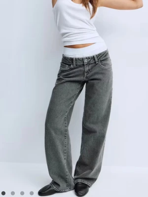 Gråa baggy jeans med raka ben lowwaist  - Säljer ett par gråa baggy jeans med raka, vida ben och låg midja. Jeansen har klassiska fem fickor och tydliga sömmar. Perfekta för en avslappnad och trendig look. Materialet är denim i bomull.