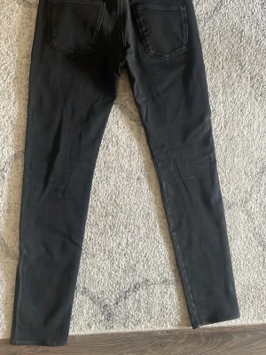 Replay Anbass - Säljer ett par svarta skinny jeans med klassisk femficksdesign och smal passform. Jeansen har raka ben och är tillverkade i ett stretchigt material som sitter snyggt. Perfekta till en avslappnad eller trendig look.