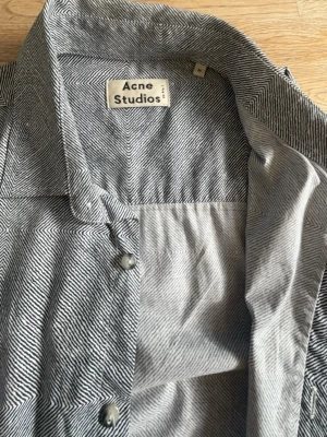 Randig skjorta från Acne Studios - Snygg skjorta från Acne Studios i svartvitt randigt mönster. Skjortan har klassisk krage, knäppning framtill och långa ärmar. Perfekt för dig som gillar stilrena och trendiga plagg.
