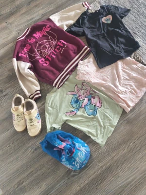 Svart Stitch t-shirt med tryck - Barnkläder med stitch t-shirtarna är 122/128 college tröjan är 130 och kepsen är barn storlek, Skorna är storlek 31 och knappt använda, finns någon fläck på kläderna 