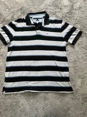 Tommy Hilfiger Randig Pikétröja (XL) - Klassisk randig piké från Tommy Hilfiger i grått, svart och blått. Custom Fit och i väldigt fint skick! 