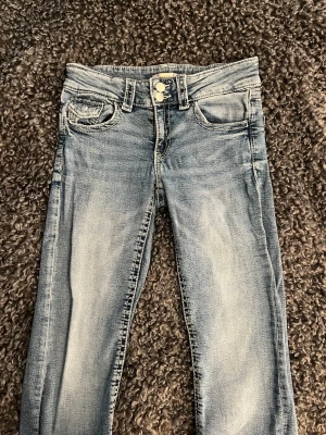 Ljusblå slim fit jeans - Snygga ljusblå slim fit jeans med klassisk femficksdesign. Jeansen har dubbla knappar i midjan och bälteshällor. Materialet är mjukt denim med en tvättad look som ger en avslappnad vibe.