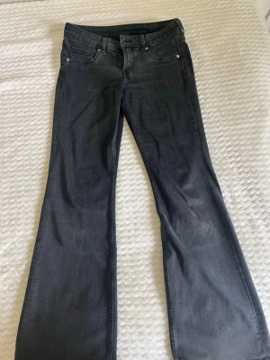 Svarta bootcut jeans - Snygga off-black lowwaist bootcut jeans med klassisk femficksdesign och normal midja. Jeansen har lätt utsvängda ben och är tillverkade i ett stretchigt denimtyg som ger en bekväm passform. Perfekta för dig som gillar en tidlös och trendig look.