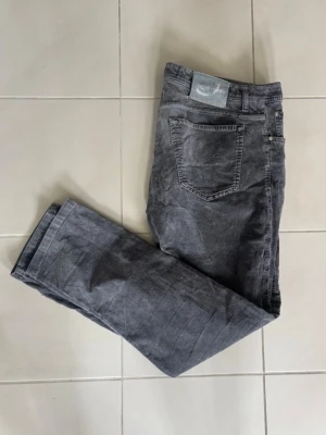 Jeans Jacob Cohen  - Mörkgråa jeans från Jacob Cohen i bra skick! Väldigt funktionell passform och badgen är i en läcker turkos färg! Ett par väldigt mångsidiga jeans som passar till allt. Längd - 103 cm och bredd - 51 cm.