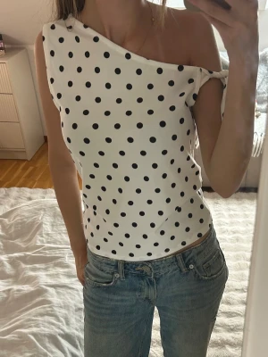 Polka dot topp - Smyg prickig top från new yorker. Storlek M men skulle säga att den är liten i storlek. Snygg knytdetalj  på ena ärmen som man kan justera.
