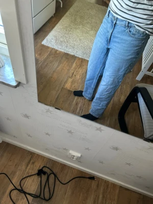 Ljusblå raka jeans med hög midja - Säljer ett par ljusblå jeans med rak passform och hög midja. Klassisk femficksmodell och stängs med dragkedja och knapp. Jeansen har en avslappnad look och är perfekta till vardagsoutfits. Materialet är denim i bomull.