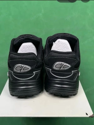 Svarta sneakers med CD-detaljer - Snygga svarta sneakers  med tydliga CD-loggor på hälen och tryck på innersulan. Skorna har en chunky sula, mesh och syntetmaterial samt reflekterande detaljer längs ovandelen. Perfekta för dig som gillar streetwear och exklusiv design.