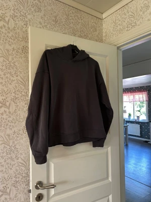 Mörkgrå hoodie - Säljer en mörkgrå oversized hoodie med huva och långa ärmar. Hoodien har en enkel och clean design utan tryck eller detaljer, och är tillverkad i ett mjukt sweatshirtmaterial. Perfekt för en avslappnad och chill stil.