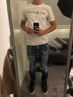 Desquared jeans - Säljer ett par blå jeans från Desquared med slitningar och snygga detaljer. Storlek 44, vilket motsvarar ca W30 L30. Modellen är 175 cm lång