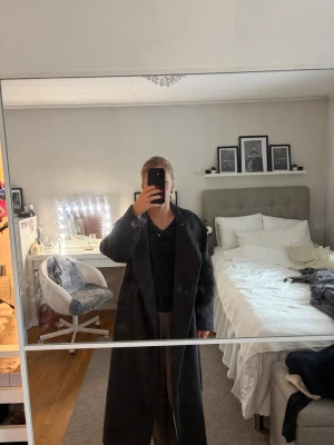Lång kappa  - Säljer denna snygga långa kappa från Nelly som är perfekt nu när hösten kommer och även till vintern. Den har hög krage som man kan knäppa men även bara ha upp vikt samt ett knytbälte. Är lite fluffig material. Ett litet hål i ena fickan men de skulle gå att bara sy ihop. Ny pris 999kr på Nelly. 
