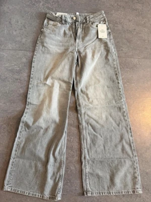 Gråa raka jeans med hög midja - 🌸Säljer ett par gråa jeans med rak passform och hög midja. Jeansen har klassiska fem fickor och vida ben. Materialet är denim i bomull och färgen är ljusgrå med en tvättad look. Perfekta för en avslappnad och trendig stil.