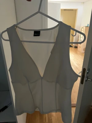 Vit ärmlös linnetopp Gina Tricot - Säljer en vit topp från Gina Tricot i storlek M. Toppen har en v-ringning och är vit / beigevit. 