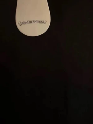 Svart tröja från Chrome Hearts - Svart tröja från Chrome Hearts med logga på bröstet. Tröjan har en klassisk rak passform, ribbade muddar och är tillverkad i ett mjukt material som känns skönt mot huden. Perfekt för dig som gillar stilren streetwear med exklusiv känsla.