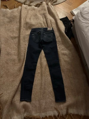 Mörkblå tajta jeans från true religion  - Säljer ett par mörkblå skinny jeans med låg midja, snygga bakfickor och fina detaljer från True religon, jeansen är i bra skick, men på ena låret är det en fläck, de är perfekt till dig som söker ett par snygga jeans!😻😻😻