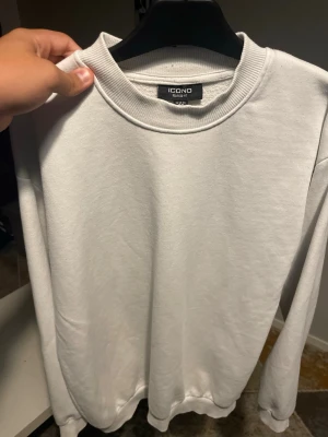 Vit sweatshirt från ICONO - Klassisk vit sweatshirt från ICONO i relaxed fit. Tröjan har rund halsringning, långa ärmar och ribbade muddar vid ärmslut och nederkant. Perfekt basplagg för en clean och enkel stil.
