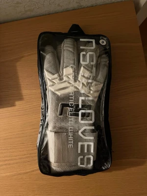 Ns1 Chromatic Elite - white målvaktshandskar - Säljer ett par välanvända men fortfarande funktionsdugliga Ns1 Chromatic Elite  målvaktshandskar.  Skicket är använt – se bilder för detaljer. Slitna i handflatorna och något smutsiga, men passar perfekt som ett extra par för träning eller som backup.   Storlek: 9 Nypris: 799kr   Skicka ett meddelande vid intresse!