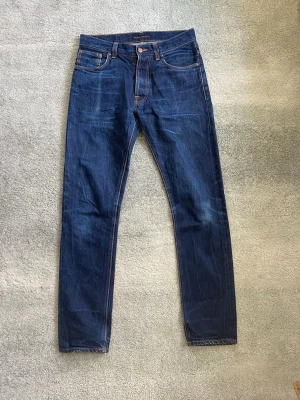 Nudie jeans grim tim  - Ett par snygga marinblåa Nudie jeans i storlek 30/34. Han på bilden är 179. Högra fickan är igensydd pga hål i fickan, men är lätt att laga. Annars fint skick. Har du några frågor? Fråga på