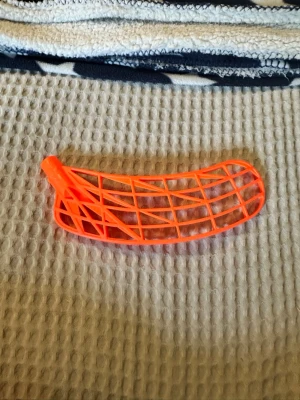 Innebandyblad i neonorange plast - Säljer ett innebandyblad i starkt neonorange färg. Bladet är tillverkat i plast och har ett klassiskt rutnätmönster med böjd form, perfekt för att montera på ett innebandyskaft. Passar dig som vill sticka ut på planen. PE plast helt nytt oanvänt och är för er rightare.