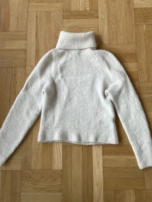 Vit stickad polotröja - Mysig vit stickad polotröja med hög krage och rak passform, perfekt för kalla dagar. Materialet är mjukt vilket ger en skön och varm känsla. Jag köpte den här på plick men passade tyvärr inte mig💕