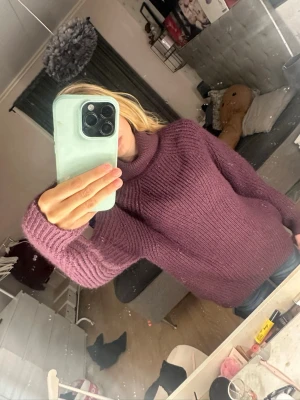 Lila stickad polotröja - Mysig lila stickad polotröja med grov ribbstickning. Tröjan har en hög krage och långa ärmar, perfekt för kyliga dagar. Passar dig som gillar en avslappnad och trendig stil.