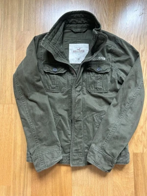 Grön Hollister jacka  - Säljer denna Hollister jackan i storlek M. Modellen är 175 väger 65kg och har storlek S.  Längd 67cm Armlängd 69cm  Bredd 50cm